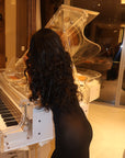 Woman in black dress at clear piano
